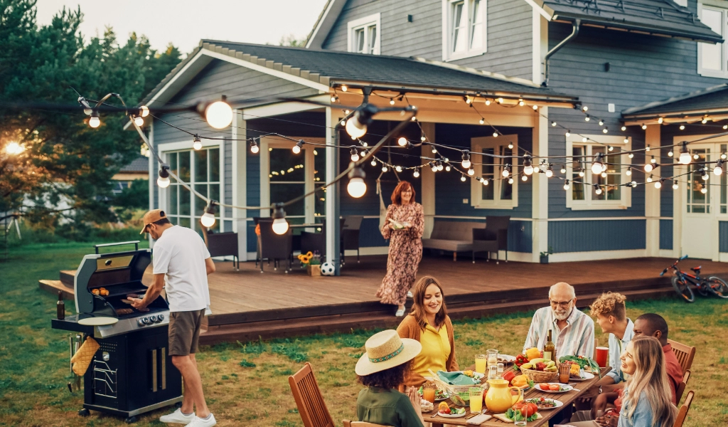A group of people having a barbecue in the backyard of a house that was painted by a professional painter.