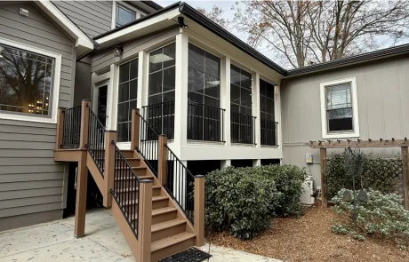 A two-story gray house with a glass-enclosed sunroom is complete with a professional painting project.