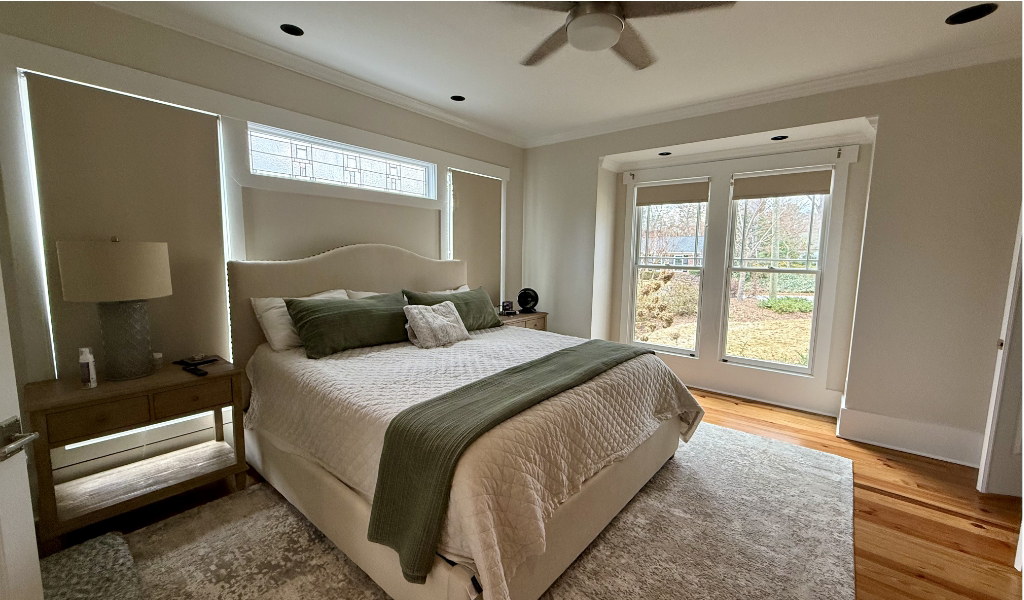 A bedroom painting project brings life to this serene space, featuring a large bed with green and white bedding, flanked by two nightstands.