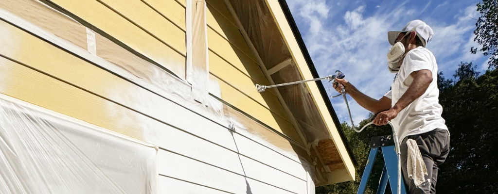An employee from a professional house painting company painting the exterior of a home.